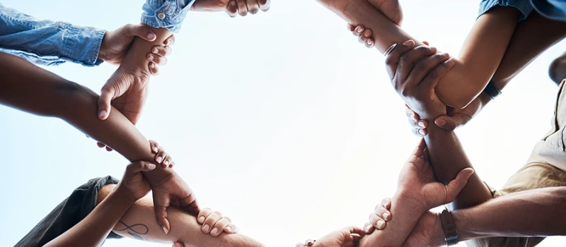 A groupf of diverse team members putting their hands together to forma circle